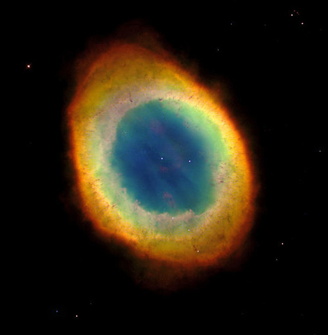 The colors of the vibrant Ring Nebula suspended in the black of space. The ovular shape is filled with a rainbow of colors, especially out toward the edges
