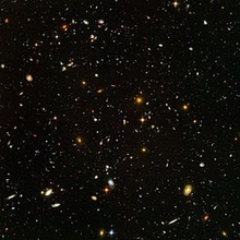 Thousands of small, colorful galaxies are seen on a black background.