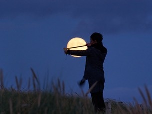 moongames_lavedern080717_94_med (1).jpeg A person stands in twilight in a field, measuring the size of the Moon from their perspective with a measuring tape.