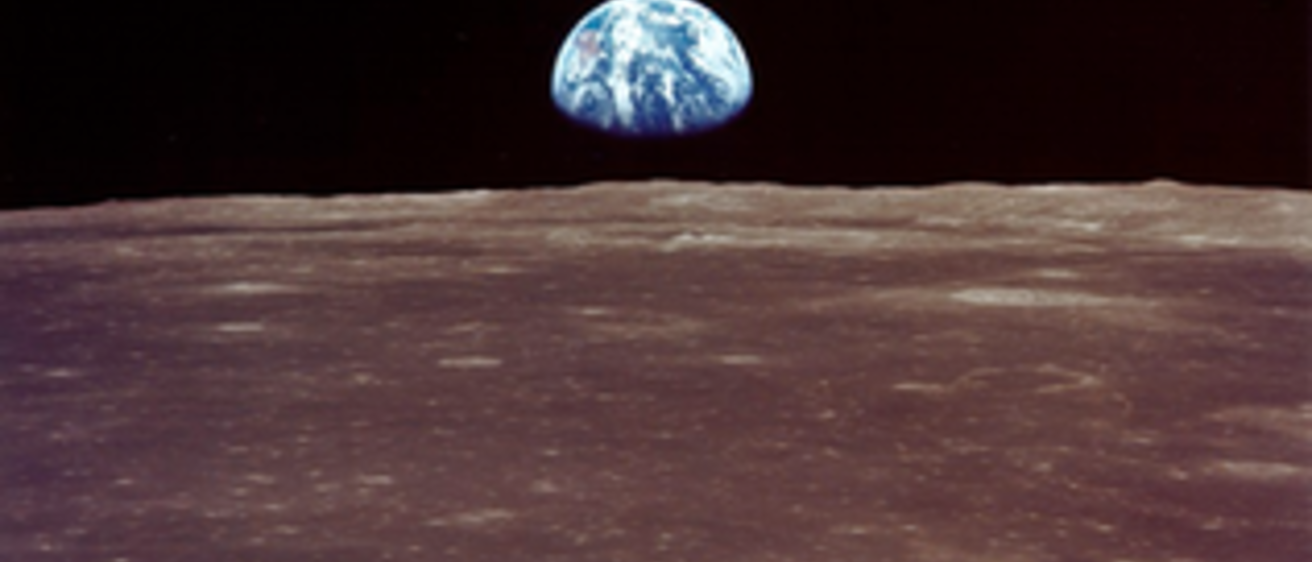 A First Quarter Earth is seen just above the Moon’s horizon; this photo is from humans’ trips to the Moon